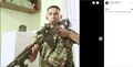 Позирование со снайперской винтовкой в бытовой обстановке на фоне футболки с эмблемой-калькой с германского орла.